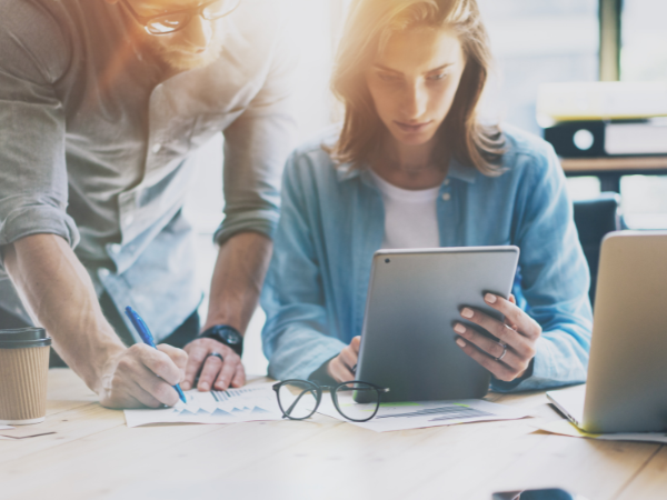 Two business professionals engaged in a collaborative work session, with one person holding a tablet and the other reviewing documents, reflecting the effectiveness of leadership training by Integrity Solutions Australia.