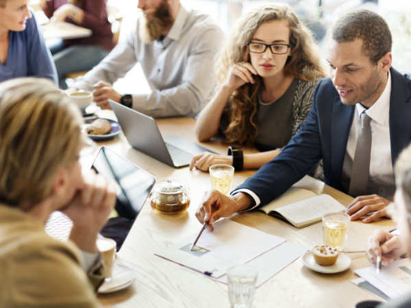 A business team collaborating around a table, actively discussing and working on a project, illustrating the focus on communication skills development by Integrity Solutions Australia.